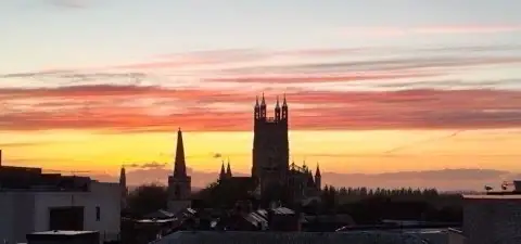 Gloucester Cathedral silhouetted against a sunset sky